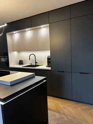 Czarna wysoka zabudowa kuchenna z podświetloną wnęką i wyspą