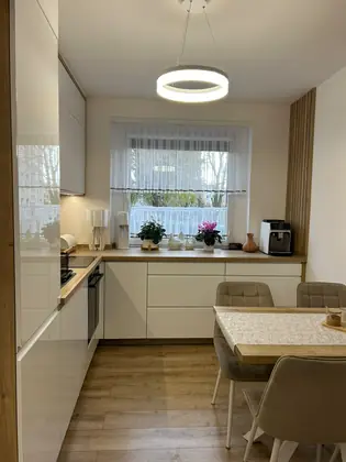 Biała kuchnia z jadalnią i okrągłą lampą
