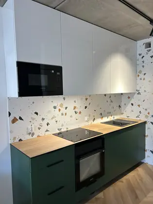 Zielona kuchnia z drewnianym blatem i płytkami lastryko